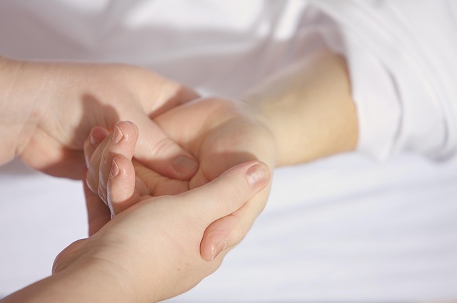 Les mains d'une praticienne massent la main d'une personne, en pression douce et progressive